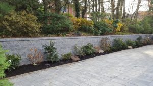 a paver driveway job with a retaining wall and a green fence in Englewood Cliffs NJ completed 3