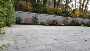 a paver driveway job with a retaining wall and a green fence in Englewood Cliffs NJ completed 4
